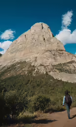 the person is walking down the path to get on the hike