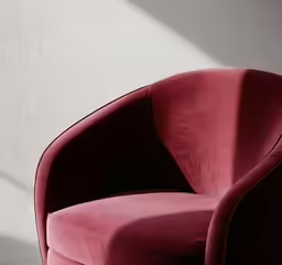 a red chair with white wall and windows in background