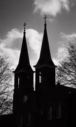 two black church towers and a cloudy sky