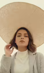 a woman wearing a beige hat in front of a white background