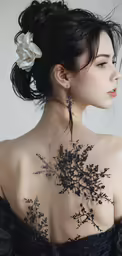 a young woman in a dark dress with an intricate back tattoo