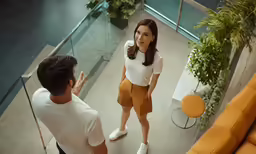 the woman is standing near a man in white shirt and brown shorts