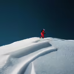 a person in red jacket on snowboard down slope