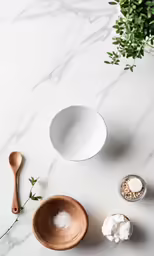 a marble surface with some salt and a wooden spoon