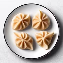 five dumplings sitting on top of a white plate