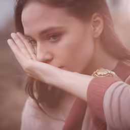 a beautiful young woman looking down while holding her hand over her face