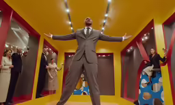 a man in a suit standing in a room filled with mirrors