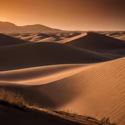a sun setting in a desert with sand dunes and hills