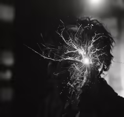 a man holds a lit sparkler over his face