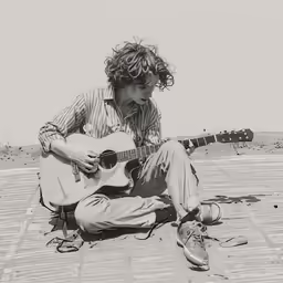 a man that is sitting down with a guitar