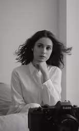 a woman sits in bed looking at the camera