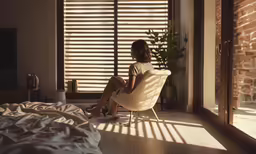 a young woman sitting in an armchair on her legs looking outside