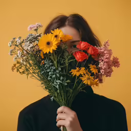 a woman holding a bouquet of flowers while wearing a black shirt