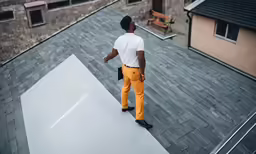 a man on the roof in bright orange pants