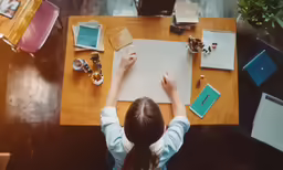 there is a girl at the table and making a sign