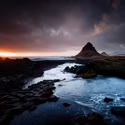 a small river flowing between rocky hills under a cloudy sky