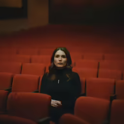 a woman stands in front of a red row of chairs