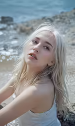 the blonde girl is posing on the beach