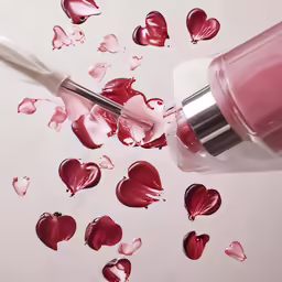 lip butter being poured onto lips with the lipstick brush