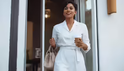 a woman holding a bag and smiling and holding a coffee