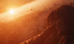 a person is holding her head up with the sun shining behind them