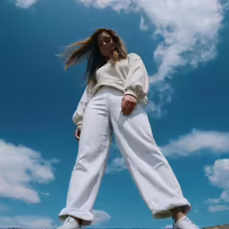 a woman in white is standing outside with her arms crossed