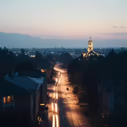 street lights are streaking along the buildings, with a town in the distance