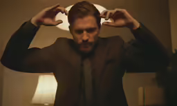 man adjusting his hair while looking at the camera