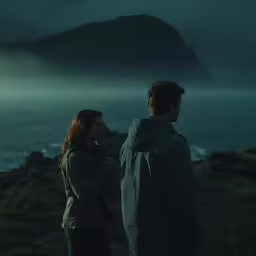 the man and woman are standing next to each other near the ocean
