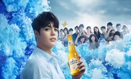 a man holding up a beer standing in front of a blue background with lots of people