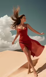 a beautiful woman in a red dress runs on a sand dune