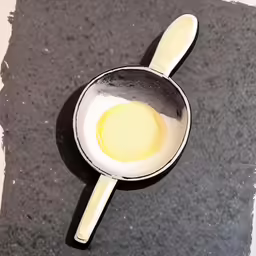 a pan containing yellow sauce with spoon on the floor
