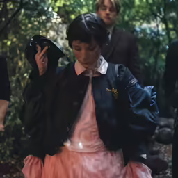 young girl holding onto her jacket in a crowd of people