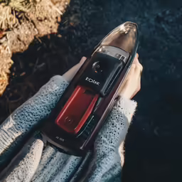 person holding a cell phone in a bag