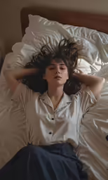 a woman laying in a bed with her hand under her head