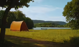 a tent sitting in the grass next to a lake