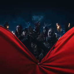 the group of people in the red cloth are standing around with umbrellas