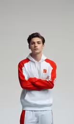 a young boy in red and white with his arms crossed