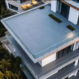 an architectural building with a metal roof and green bushes on it