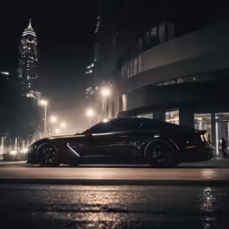 black sports car in front of large buildings at night