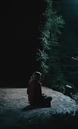 a woman sitting on top of a dirt road near a forest