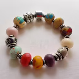 colorful bead bracelet with silver accents on white background,a bead bracelet that is colorful and has skulls on it