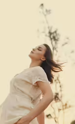 an attractive woman standing near a tree and looking up