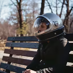 a woman with a helmet sits on a bench