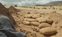 a man who is walking in the dirt by some rocks