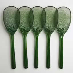 four green handmade glass scoops lined up in a row