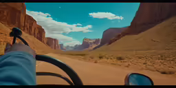 a man holding up his hand while riding a bus through the desert
