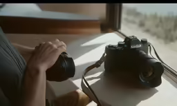 a person holding a camera over a window sill