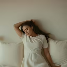 a woman laying in bed on top of a pillow