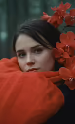 a woman wrapped in a red blanket near a tree
